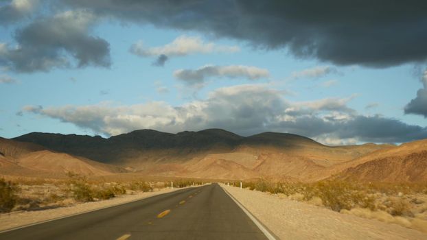 Road trip, driving auto from Death Valley to Las Vegas, Nevada USA. Hitchhiking traveling in America. Highway journey, dramatic atmosphere, sunset mountain and Mojave desert wilderness. View from car.