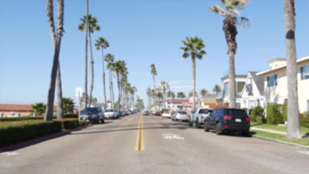 Defocused road with palm trees in California, Oceanside tropical beach resort, USA. Waterfront street near pacific ocean. American summertime, Los Angeles Hollywood aesthetic. Yellow dividing line.