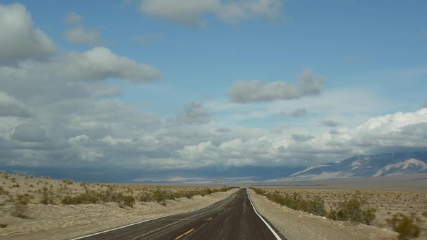 Road trip to Death Valley, driving auto in California, USA. Hitchhiking traveling in America. Highway, mountains and dry desert, arid climate wilderness. Passenger POV from car. Journey to Nevada.