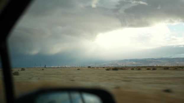 Driving auto, road trip in California, USA, view from car. Hitchhiking traveling in United States. Highway, mountains and cloudy dramatic sky before rain storm. American scenic byway. Passenger POV.