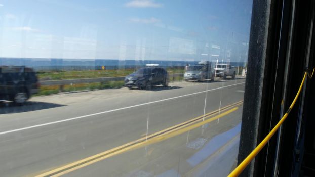 View from bus window, pacific coast highway 1, freeway 101 historic route, California USA. Road trip in public passenger transport. Journey along summer ocean or sea near Los Angeles. Yellow cord.