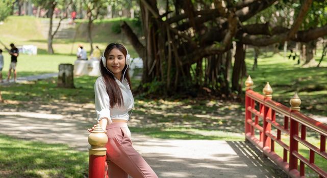 Portrait Asian Student Girl Wearing Headphones, Standing On Lawn In Park,