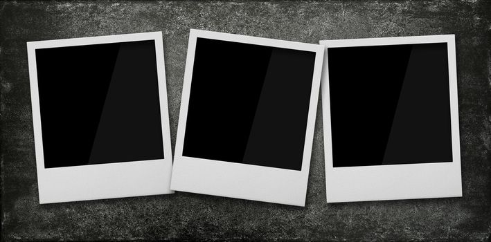 Close up three empty Polaroid instant photo frames on grunge black stone table background, elevated top view, directly above