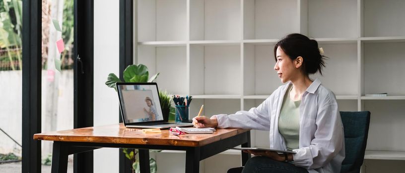 Cropped photo of woman writing making list taking notes in notepad working or learning on laptop indoors- educational course or training, seminar, education online concept.