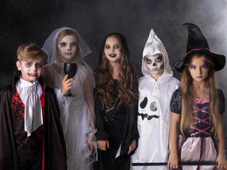 Happy Halloween party with children trick or treating in different costumes ghost, vampire, skeleton, witch
