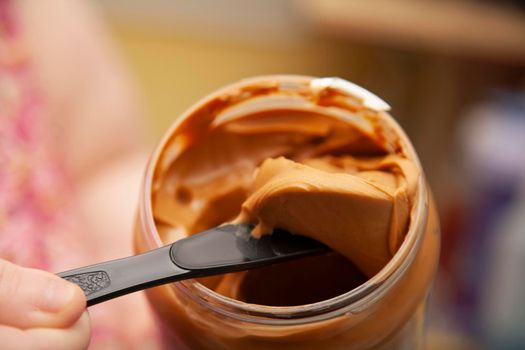 Plastic knife digging out peanut butter from a jar