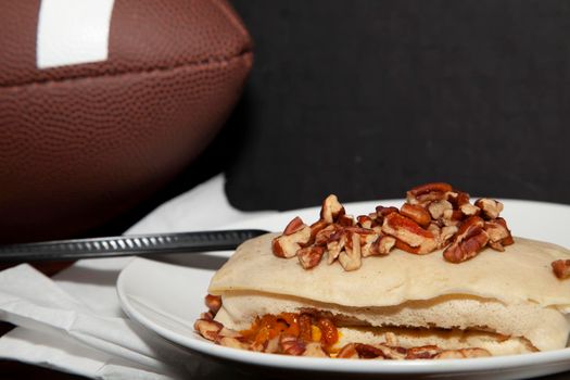 Football next to a pecan covered burrito and a napkin