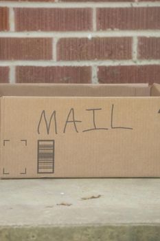 Cardboard box with the word MAIL written on it on a porch