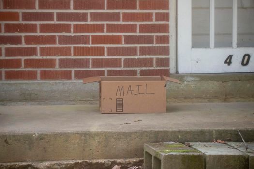Cardboard box with the word MAIL written on it on a porch
