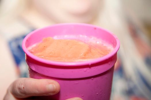 Woman holding a pink cup filled with a pink icy drink