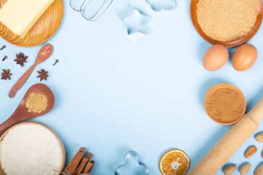 Christmas gingerbread cookies cooking background flat lay top view template with copy space for text. Baking utensils, spices and food ingredients on blue background