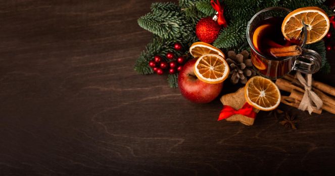 Mulled wine with cinnamon sticks orange fir tree branch and baubles Christmas composition over dark wooden background