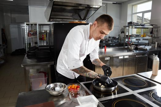 Professional chef cooking in the kitchen in hotel restaurant, preparing salad with shrimps