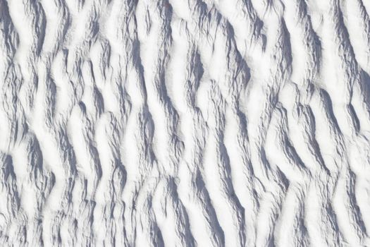 White texture of Pamukkale calcium travertine in Turkey, pattern of vertical waves, close-up.