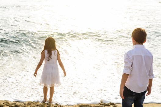 Children looking at the sea with his back to the camera with the sunset