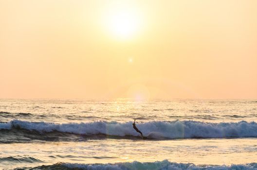 Surfing at Sunset. Young Man Riding Wave at Sunset. Outdoor Active Lifestyle.