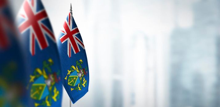 Small flags of Pitcairn Islands on a blurry background of the city.