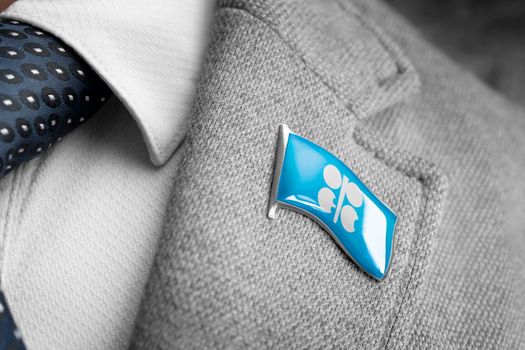Metal badge with the flag of Organization of the Petroleum Exporting Countries on a suit lapel.