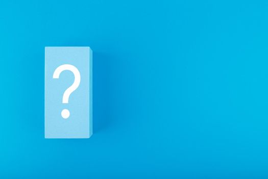 White question mark on blue background with copy space. Flat lay, trendy minimal composition with question