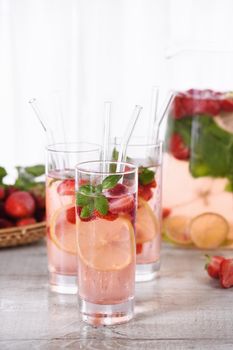 Summer strawberry cocktail or lemonade with basil. Cold refreshing organic soft drink with ripe berries in a glass