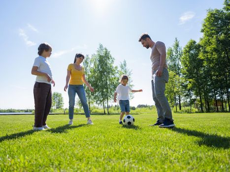 Parents and kids playing soccer ball together in park