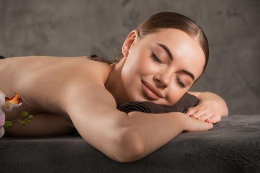 Close up of a smiling woman relaxing on a lounger with eyes closed in a wellness center