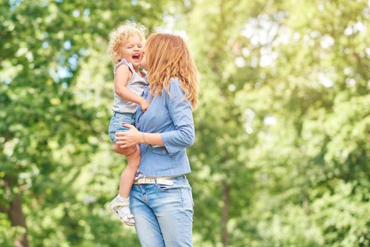 Shot of a loving mother holding her cute baby girl kissing her on a cheek while outdoors at the park copyspace motherhood parent happiness love family children kids concept.