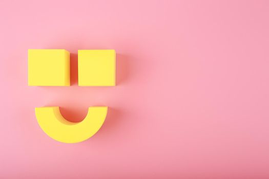 Creative flat lay with yellow happy smile symbol made of figures on pink background with copy space. Concept of Smile day, emotions, emoji or mental health