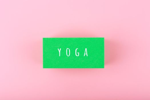 Single word yoga written on green rectangle on bright pink background. Concept of signboard for yoga class or courses or template for website or banner