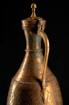 Part ancient oriental metal jug on dark background. Antique bronze tableware