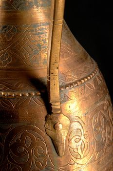 Part ancient oriental metal jug on dark background. Antique bronze tableware