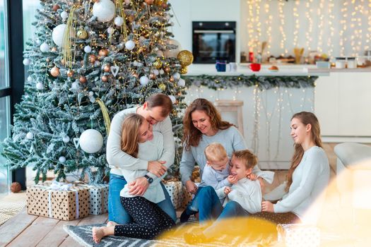 Happy family with four sibilings near the Christmas tree with the present boxes. Christmas family morning, christmas mood concept