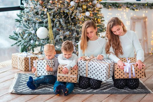 Happy kids sibilings near the Christmas tree with the present boxes. Christmas morning, christmas mood concept