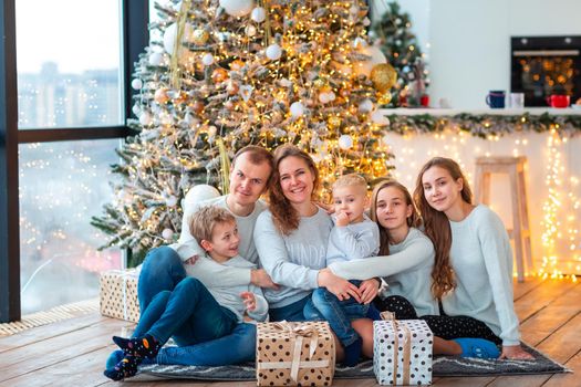 Happy family with four sibilings near the Christmas tree with the present boxes. Christmas family morning, christmas mood concept