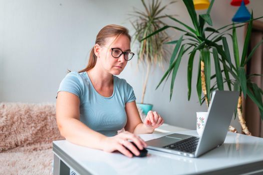 Middle age woman sitting at the table at home working using computer laptop. Work from home and stay at home during coronovirus pandemic concept