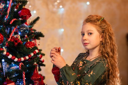 Happy little girl decorating the Christmas tree at Christmas eve. Christmas morning, christmas mood concept