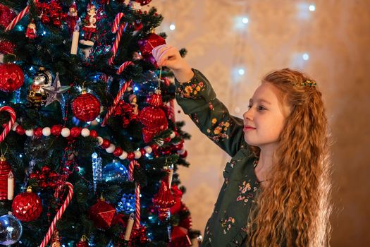 Happy little girl decorating the Christmas tree at Christmas eve. Christmas morning, christmas mood concept