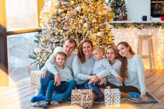 Happy family with four sibilings near the Christmas tree with the present boxes. Christmas family morning, christmas mood concept