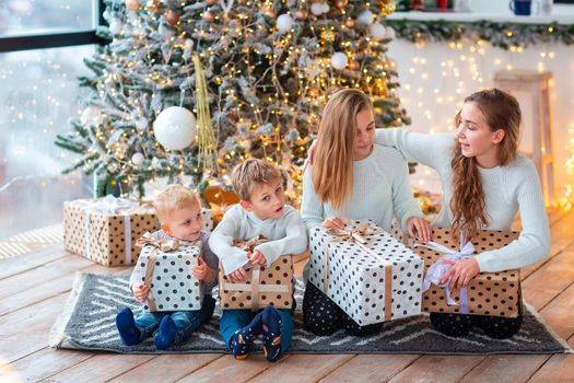 Happy kids sibilings near the Christmas tree with the present boxes. Christmas morning, christmas mood concept