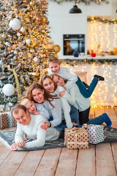 Happy family with four sibilings near the Christmas tree with the present boxes. Christmas family morning, christmas mood concept