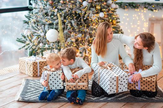 Happy kids sibilings near the Christmas tree with the present boxes. Christmas morning, christmas mood concept