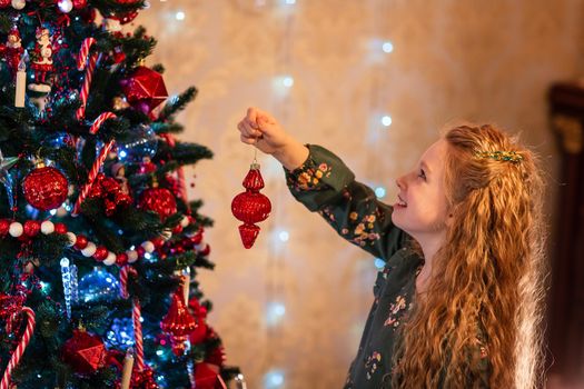 Happy little girl decorating the Christmas tree at Christmas eve. Christmas morning, christmas mood concept