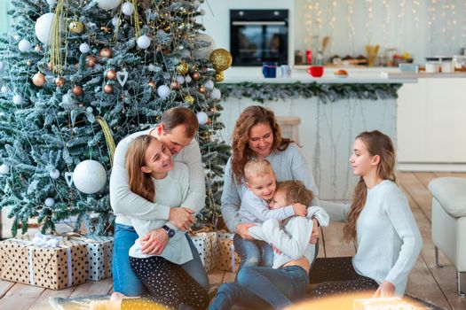 Happy family with four sibilings near the Christmas tree with the present boxes. Christmas family morning, christmas mood concept