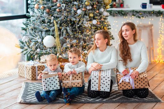 Happy kids sibilings near the Christmas tree with the present boxes. Christmas morning, christmas mood concept