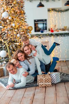Happy family with four sibilings near the Christmas tree with the present boxes. Christmas family morning, christmas mood concept