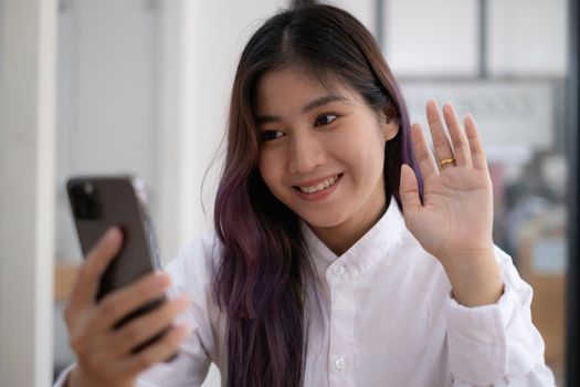 Portrait of Asian beautiful girl making video calling and waving hand for say hi by smartphone. social distancing, concept
