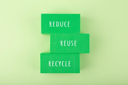 Modern minimal flat lay with reduce, reuse,recycle inscription on green rectangles against light green background. Concept of go green slogan and eco friendly lifestyle and marketing