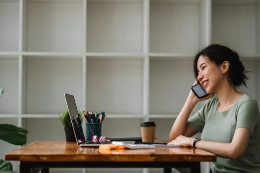 Business woman working for accounting financial and taking notes in notebook during call for consultation at home.