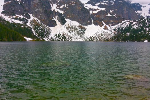 View of the lake against the backdrop of the mountain on a cloudy day