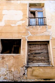 Old house facade with damaged wooden windows in Novelda village, Valencia community, Spain.